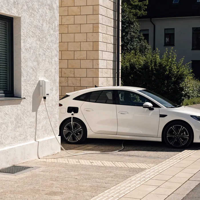 Weißes Elektroauto an einer Wallbox angesteckt